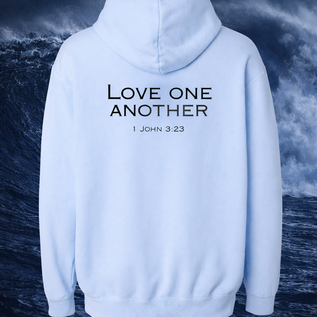White hoodie with 'Love One Another 1 John 3:23' text against a stormy ocean background