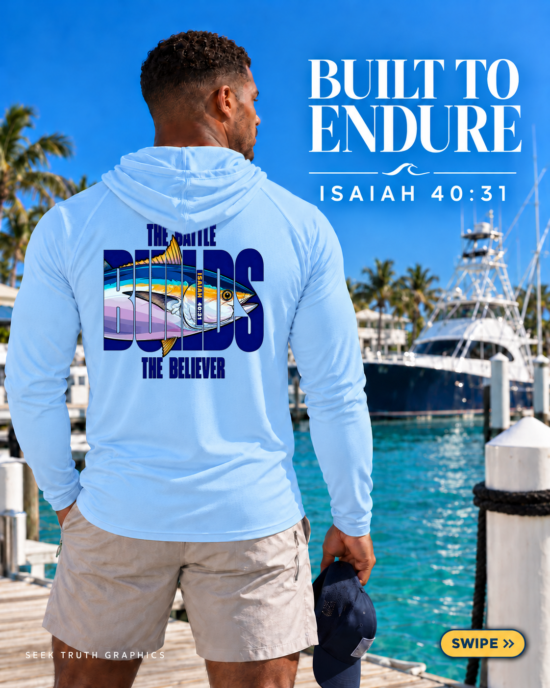 A man stands on a dock wearing a light blue long-sleeve hoodie with a large back graphic featuring a tuna fish and the text 'THE BRITTLE BUILDS THE BELIEVER.' The background shows a sunny marina with boats, palm trees, and blue water.