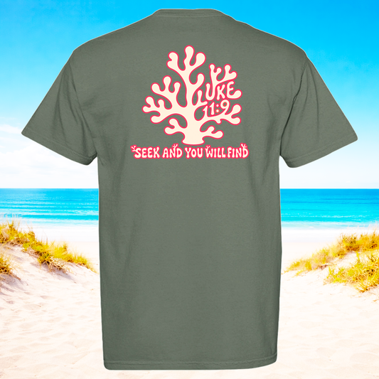 Gray t-shirt with pink coral design and text on a beach background