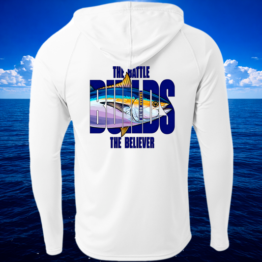 A white long-sleeve hooded shirt shown from the back, featuring a large graphic print of a tuna fish and the text 'THE BATTLE BUILDS THE BELIEVER' in blue. The shirt is displayed against a digital background of a blue ocean and sky.