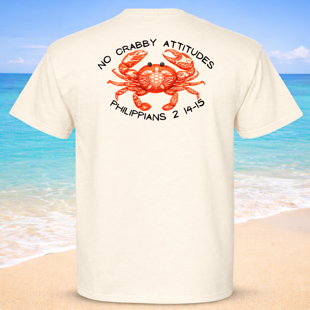 Beige t-shirt with a red crab graphic and text on the back, set against a beach background.