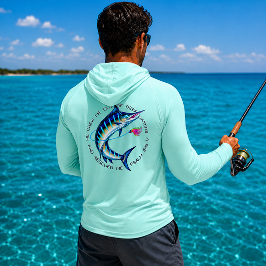 Man fishing in the ocean wearing a light blue hoodie with a fish design and text.
