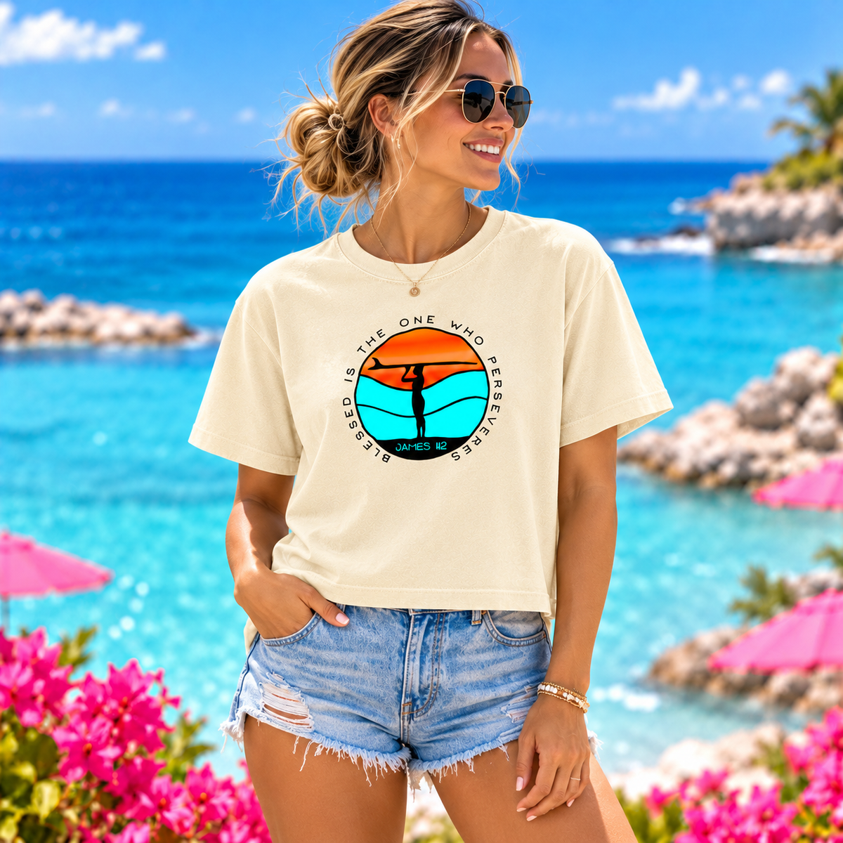 A woman stands on a tropical beach wearing a cream graphic T-shirt and denim shorts. The shirt features a circular sunset design with the text 'BLESSED IS THE ONE WHO WALKS' and 'JUNE 15'.