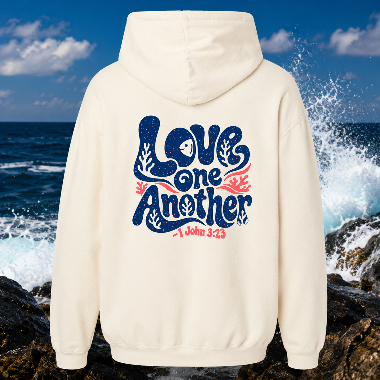 White hoodie with 'Love One Another' text on the back, against a coastal background.