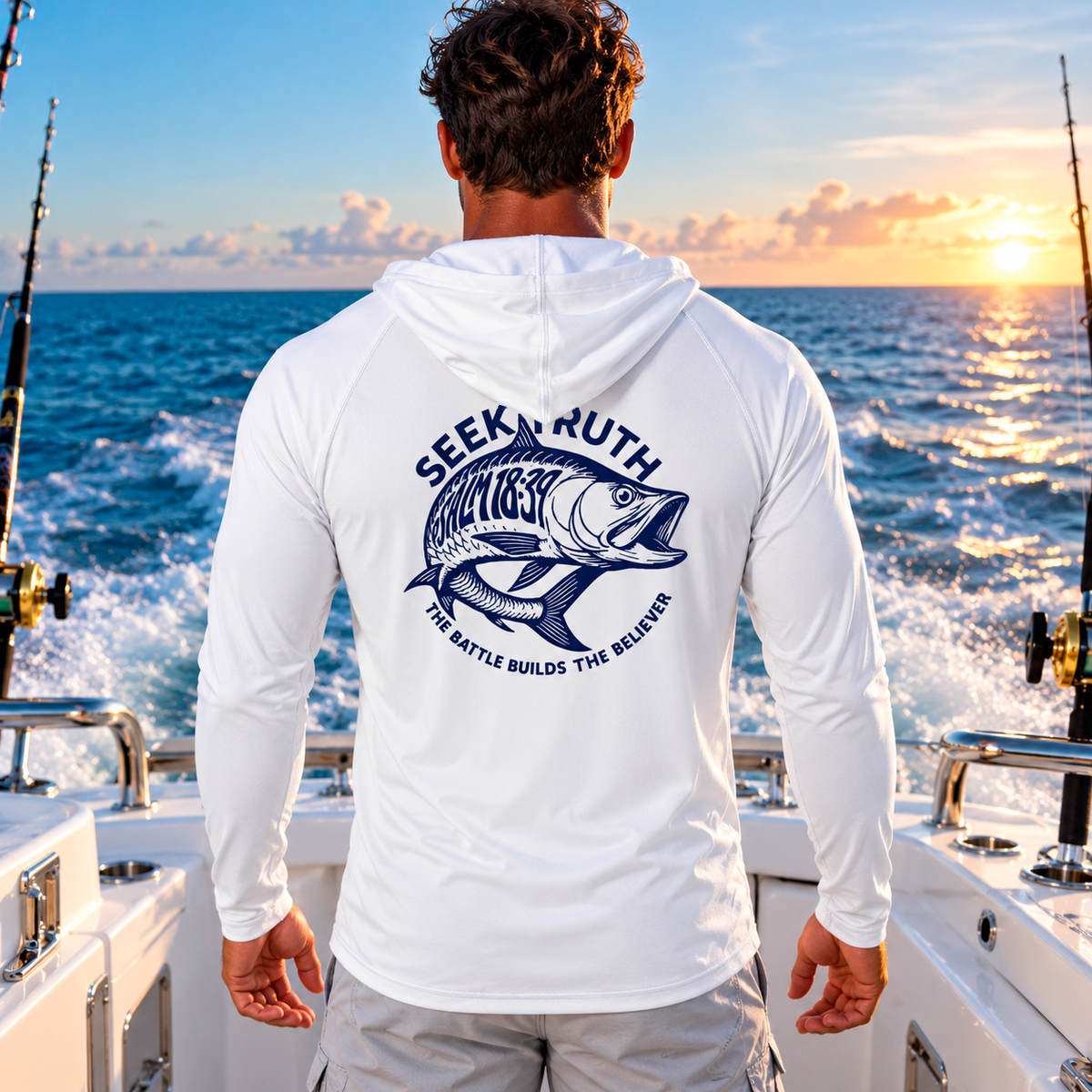 A man on a boat seen from behind, wearing a white long-sleeve hooded shirt with a large navy blue fish graphic and the words 'SEEK. TRUTH.