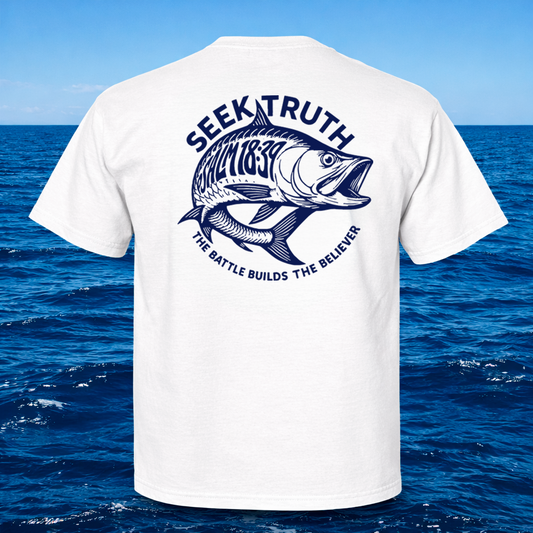A white short-sleeve T-shirt shown from the back, featuring a large navy blue graphic of a fish with the text 'SEEK TRUTH' above it and 'THE BATTLE BUILDS THE BELIEVER' below it. The shirt is displayed against a blue ocean and sky background.