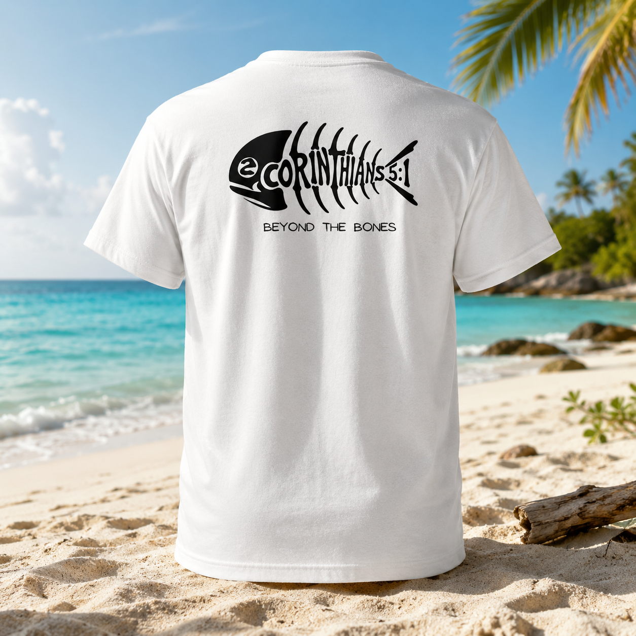A white short-sleeve T-shirt shown from the back, standing upright on a sandy beach with turquoise ocean water and palm trees in the background. The shirt has a large black fish skeleton graphic with the text 'eCORINTHIANS 3:1' and 'BEYOND THE BONES' printed on the back.