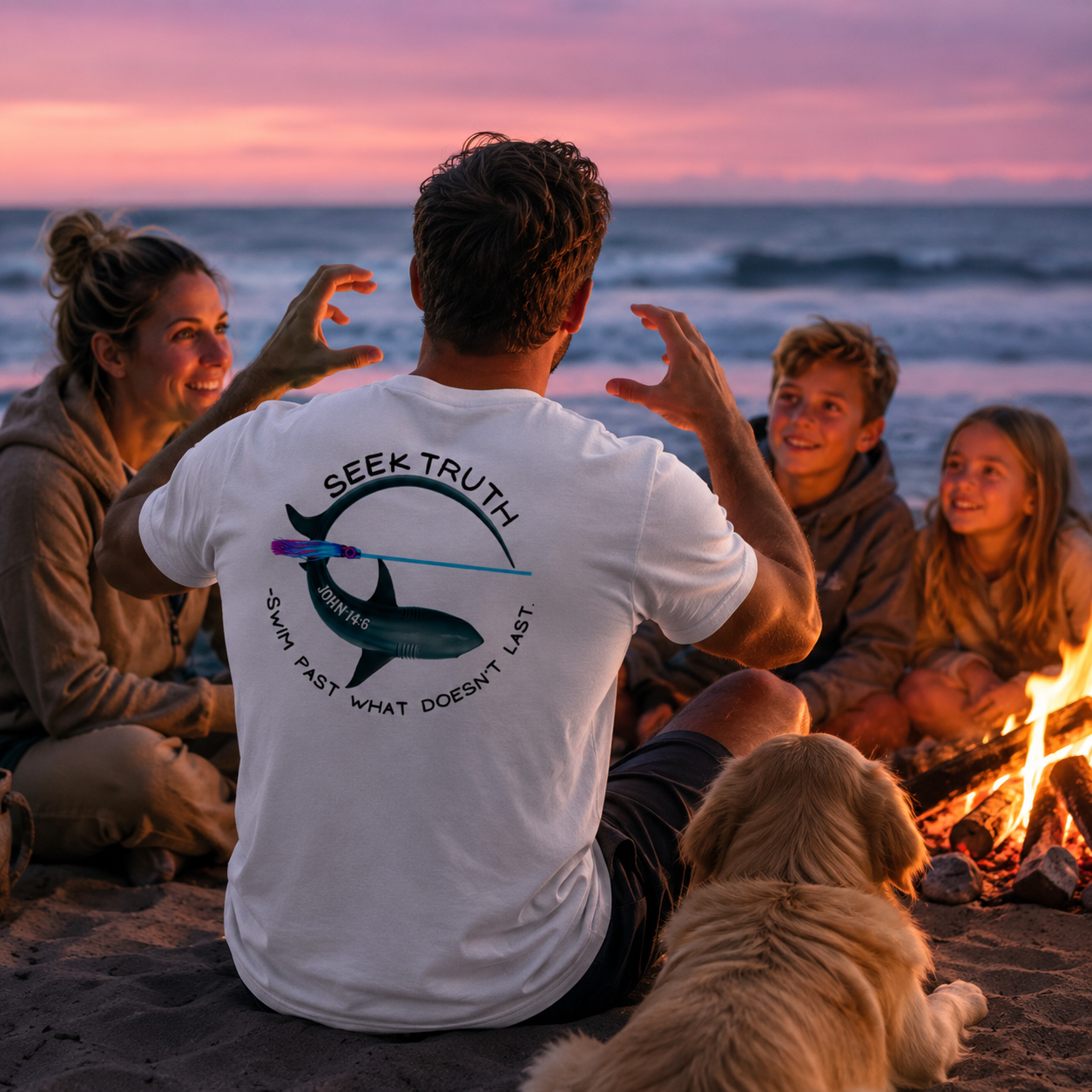 Group of people sitting around a campfire on a beach at sunset, with one person wearing a shark themed 'Seek Truth' t-shirt.