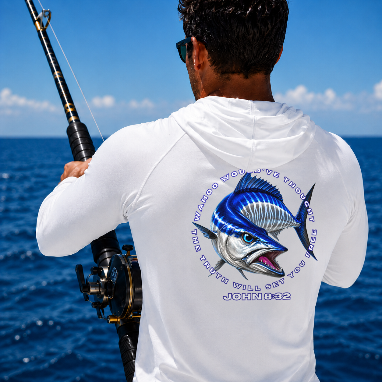 Man on a boat holding a fishing rod with a white shirt featuring a Wahoo fish design and text.